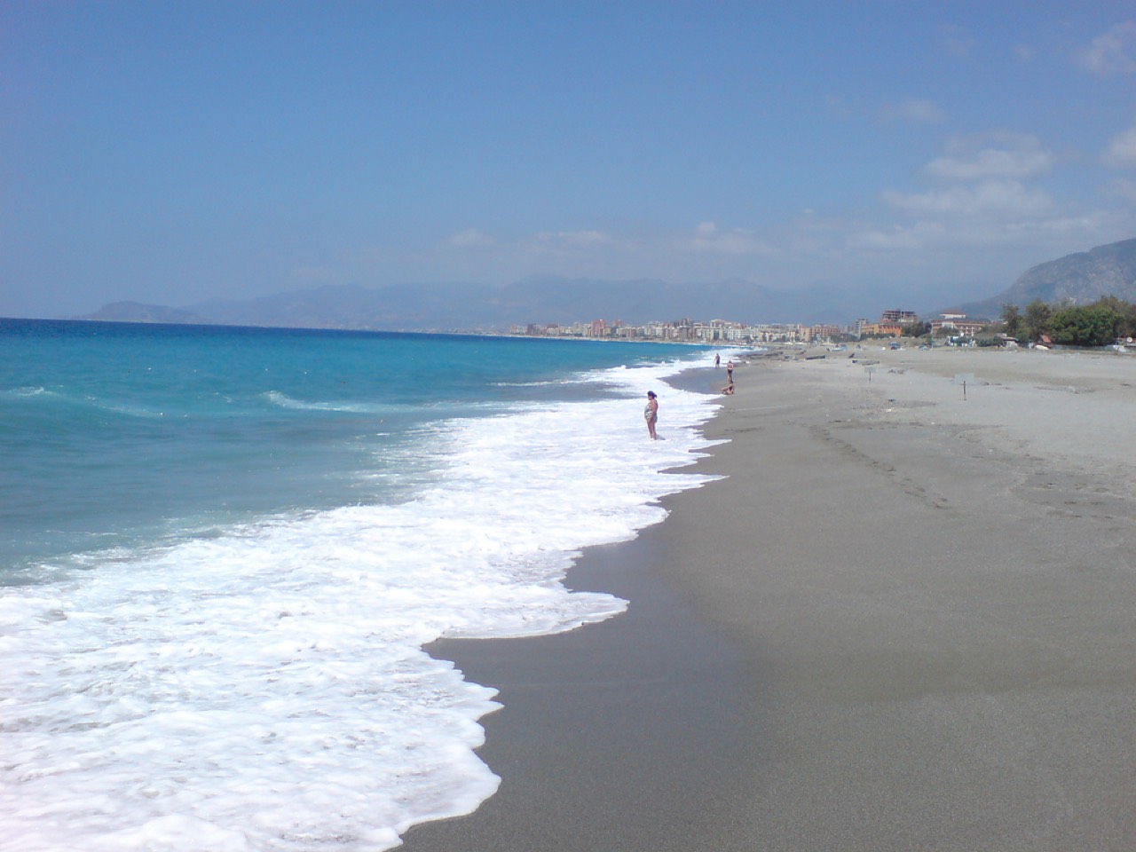 Lang sandstrand ved Keykubat Strand i Alanya med liggestole og Alanya Borg i baggrunden